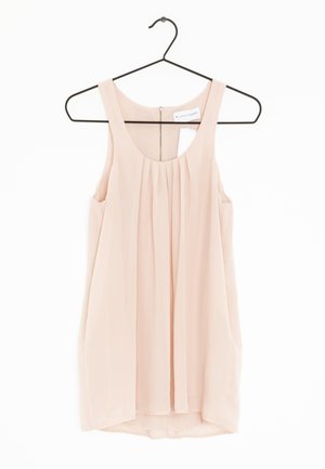 Top senza maniche di un rosa pallido, realizzato in tessuto leggero, con un design frontale plissettato e una chiusura con zip sul retro, appeso a un gancio nero.