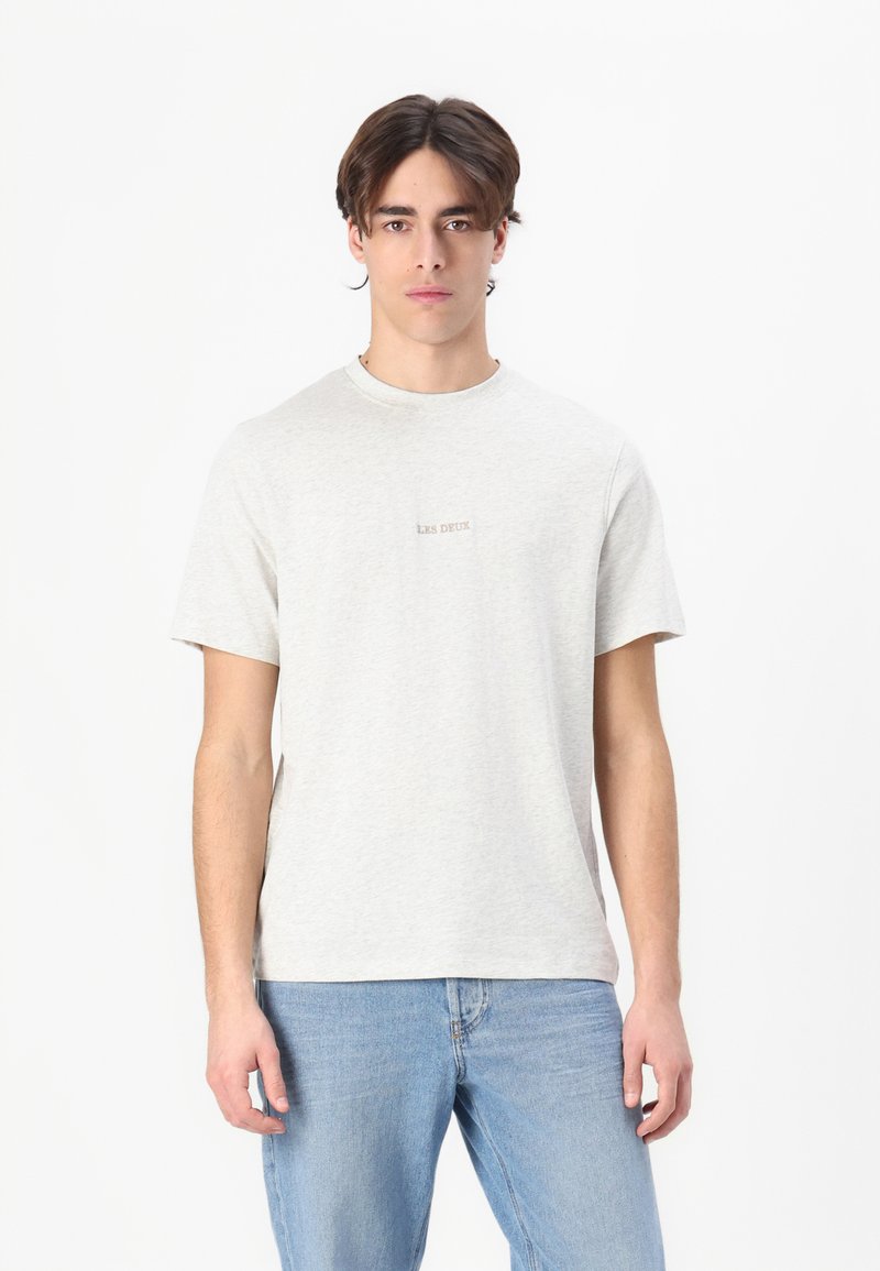 T-shirt grigio chiaro a girocollo realizzato in tessuto morbido, con il logo minimalista "LES DEUX" cucito al centro. Vestibilità casual, maniche corte.