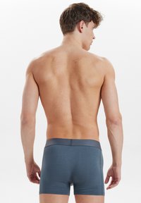 Herren Boxer-Briefs aus dunkelgrauem Stoff, weiche Textur, elastischer Bund, figurschnitt, mittellange Beine, minimale Nähdetails.