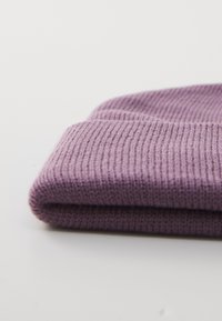 Vouwbare paarse gebreide wintermuts op een witte ondergrond, met zichtbare ribbelstructuur en details van de omslag.