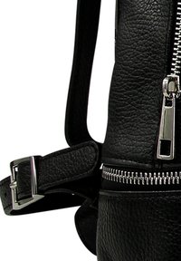 Sac à dos en cuir noir avec une surface texturée, quincaillerie argentée et un détail de fermeture éclair bien en vue sur le côté et à l'avant. Sangle à boucle visible.