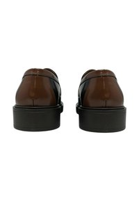 Scarpe in pelle verniciata marrone con suola nera, caratterizzate da una texture liscia e un design minimalista. Parte posteriore arrotondata senza dettagli hardware visibili.