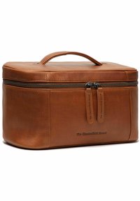 Funda de viaje de cuero marrón con textura suave, forma rectangular, asa superior, cierre de doble cremallera y marca en relieve en la parte frontal.