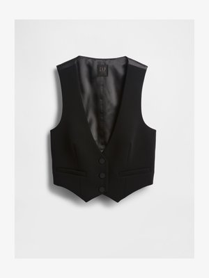 Melns vestes uzvelkams apģērbs ar dziļu V-veida izgriezumu, trim pogām un divām priekšpusē kabatām. Fakturēts audums ar gludu iekšējo oderi. Redzama zīmola etiķete.