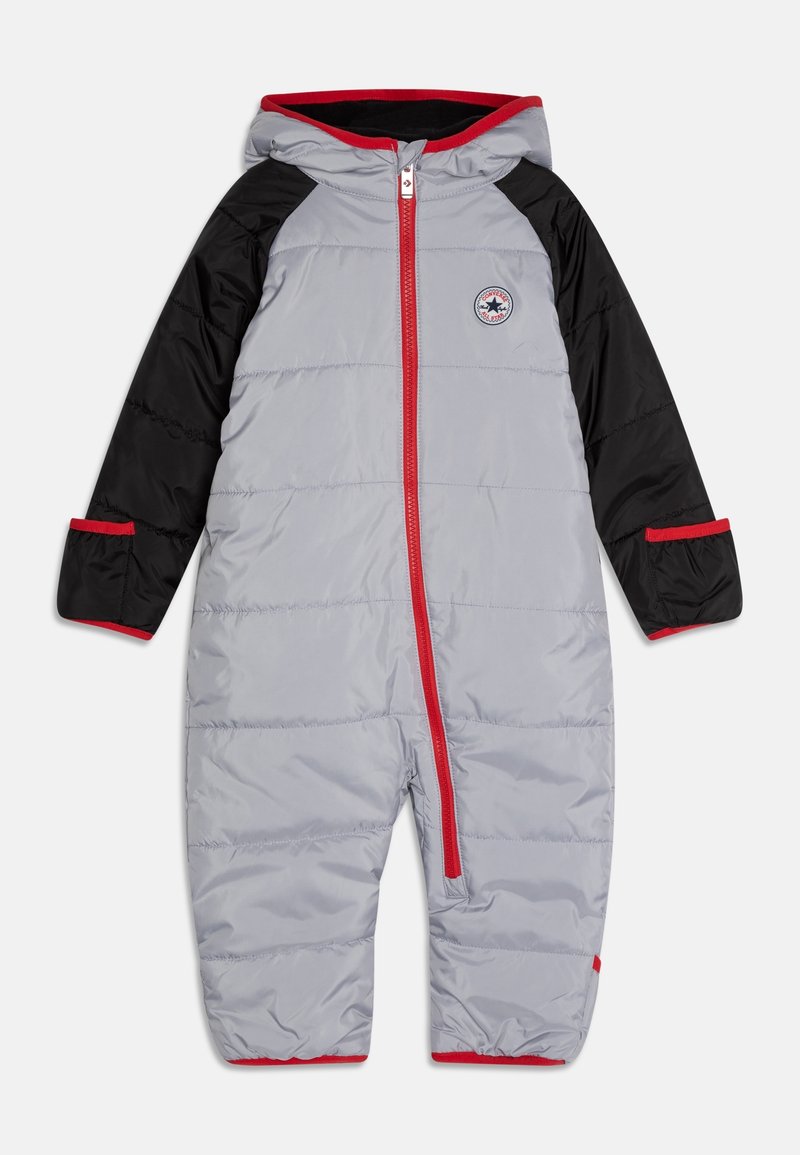 Combinaison de ski rembourrée grise avec manches noires, accents rouges et une capuche. Dispose d'une fermeture éclair à l'avant et d'un patch logo sur la poitrine. Texture douce.
