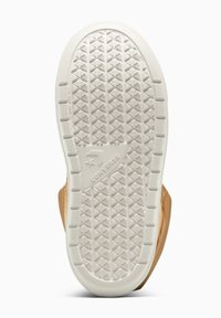 Schuhsohle mit strukturiertem, rautenförmigem Gummimuster in Weiß und einem oberem Teil aus hellbraunem Leder. Logo in der Nähe der Ferse angebracht.