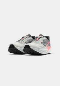 Light gray running shoes with black soles, a cushioned sole, and accents in pink. Features mesh upper and textured detailing on the sides.