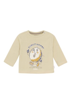 Langarm, beige katoenen shirt met een cartoon-donut met een lach, "DOENUT WORRY" tekst en blauwe accenten. Drukknopen bij de schouder.