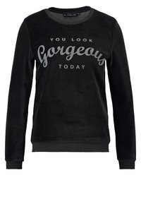 Sudadera de forro polar negra con mangas largas, cuello redondo y puños acanalados. Lleva un texto blanco que dice: "TE VES HERMOSA HOY" en la parte frontal.