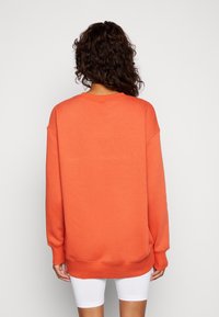 Orange oversized sweatshirt med rund halsringning, långa ärmar, ribbade muddar och nederkant. Mjuk textur, enkel design och enfärgad.