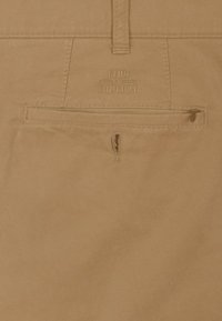 Beige chino broek met een gladde textuur, voorzien van riemlussen, een achterzak met rits en een reliëf brandnaam "CLUB COMFORT".