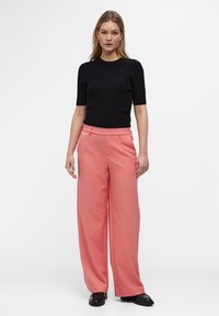 Top corto de manga corta de rayas negras combinado con pantalones de pierna ancha rosas. Los pantalones tienen una textura suave y un ajuste entallado, con bolsillos frontales.