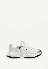 Fehér sneaker, hálós és szintetikus anyagokkal, ezüst részletekkel, vastag fekete talppal és kerek orrformával.
