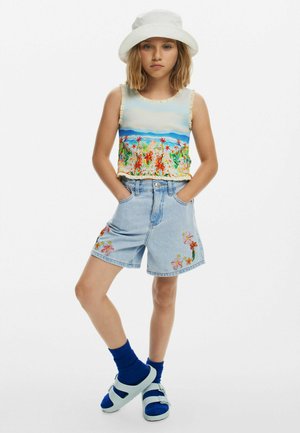 Blomstret tanktop med rynkede kanter, lyse denimshorts med blomsterbroderi, blå sokker og sandaler. Hvid bøttehat.