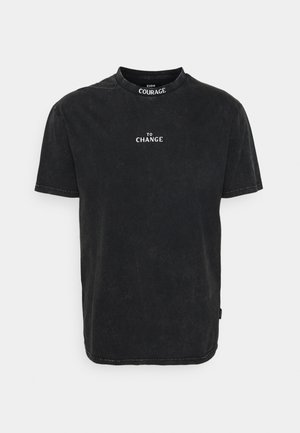 Schwarzes Kurzarm-T-Shirt mit weißem Text "TO CHANGE" mittig auf der Vorderseite und "COURAGE" auf der Innenseite des Kragens.