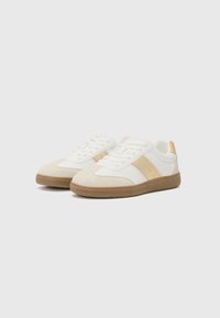 White and beige sneakers with suede and fabric materials. Features a textured gum sole, round toe, and side perforations for ventilation.