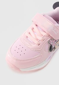 Baskets roses à finition brillante, présentant un avant perforé, un design à lacets, une bride en velcro et un motif décoratif de Minnie Mouse.