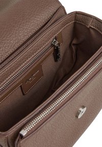 Brogas teksturēta ādas soma atvērta, lai parādītu auduma oderi ar rāvējslēdzēja kabatu un sudraba magnētisko aizdari.