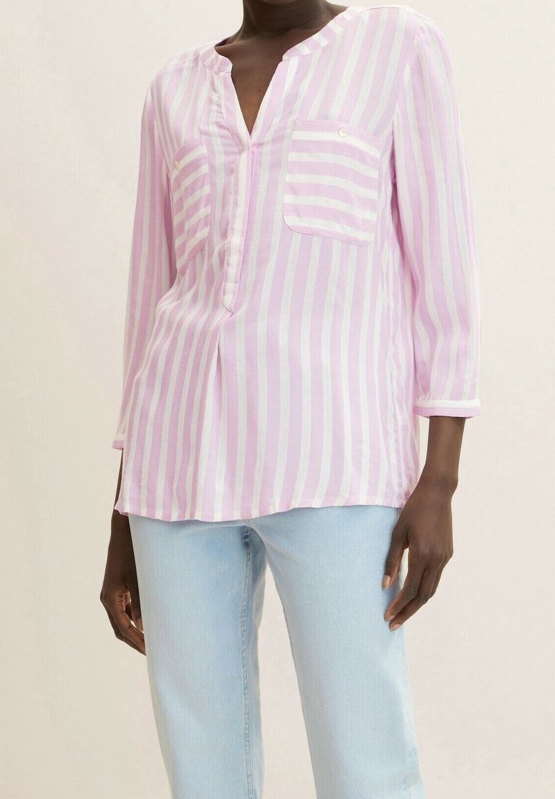 Blusa leggera a strisce rosa e bianche con scollatura a V, maniche lunghe, due tasche frontali e dettagli in bottone sul colletto e sulle maniche.