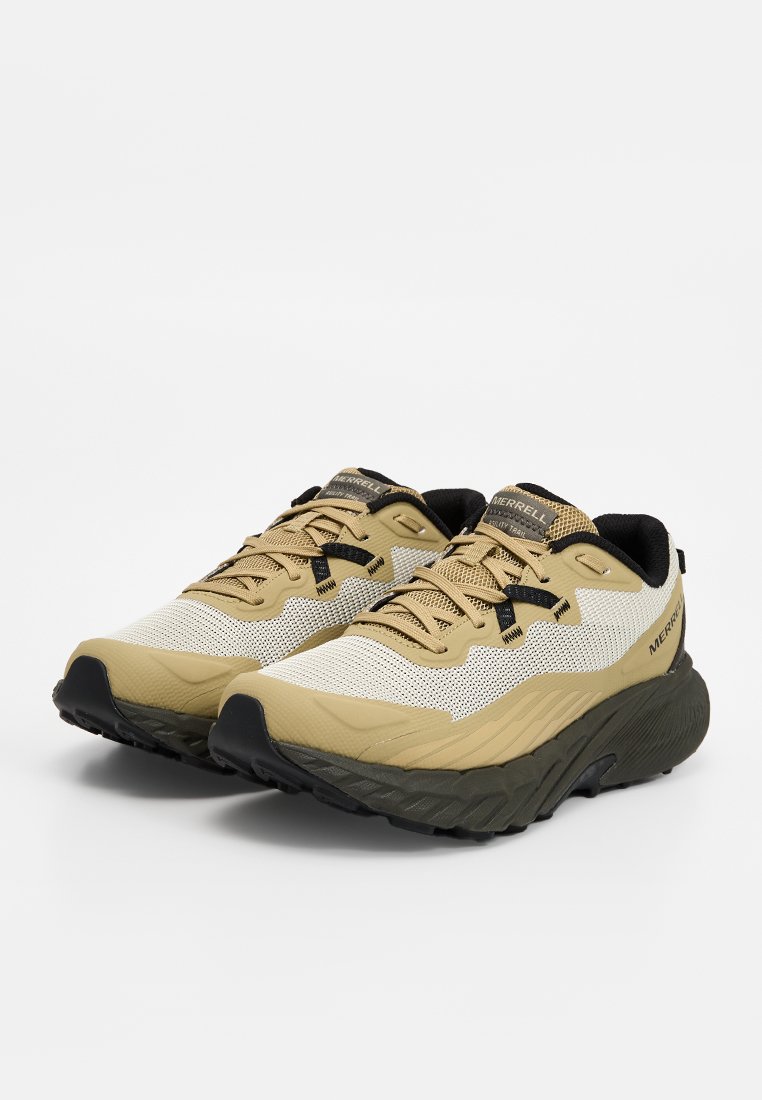 Par de zapatillas de trail running Merrell en beige y negro con parte superior de malla y suelas gruesas texturizadas, inclinadas hacia la derecha sobre fondo blanco.