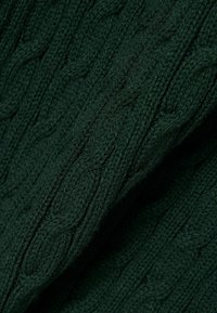 Tissu tricoté vert foncé avec un motif torsadé comportant des torsades verticales entrelacées et des points texturés.