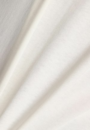 Tissu blanc doux avec une texture en maille fine et lisse, présenté en plis délicats créant des ombres et des reflets subtils.