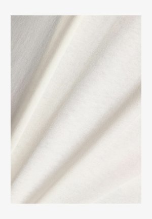 Blødt hvidt stof med en glat, fin strikket tekstur, vist i bløde folder, der skaber subtile skygger og højlys.