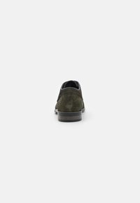 Scarpe in suede verde con una texture a motivo, accenti grigi e una suola in gomma liscia e scura, viste da dietro.