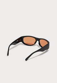 Gafas de sol negras con diseño angular, lentes tintados en naranja y montura de plástico elegante. Las varillas ligeras se estrechan hacia las puntas. Marcadas con CE.
