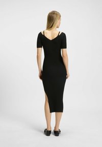 Robe midi noire côtelée avec manches courtes, dos en V et fentes sur les côtés. Dotée de bretelles ajustables pour un ajustement parfait et d'une silhouette près du corps.