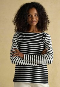 Mustvalg ja valged triibud, pikad varrukad, laeva kaelaga särk, mis on lõdva istuvusega ja pehmest kangast, valgetes mansettides.