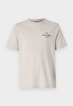 Lyse beige t-shirt med korte ærmer med lille sort "Tommy Hilfiger N.Y.C" tekst og logo på venstre bryst.