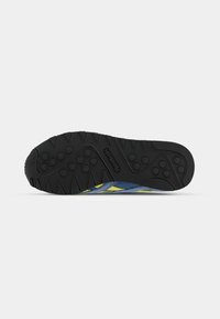 Footwear with a black rubber sole featuring a textured grip pattern, blue textile upper with yellow accents, and athletic design elements.