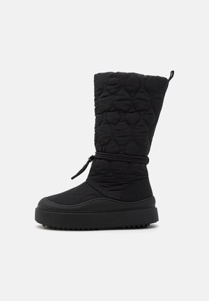 Botas de invierno acolchadas negras con un eje texturizado, cordón ajustable y una suela gruesa tipo plataforma para mayor comodidad y soporte.