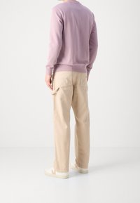 Světlofialová mikina s dlouhými rukávy, doplněná béžovými cargo kalhotami. Jednoduchý design, volný střih a zadní kapsy. Bílé tenisky.