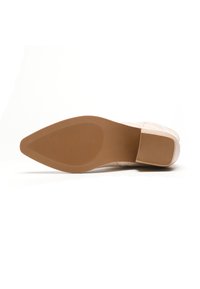 Zapato de color rosa claro con parte superior texturizada y puntera afilada. La suela es de goma marrón con líneas horizontales para un mejor agarre.