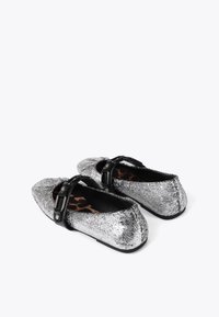 Srebrne baleriny z popękaną teksturą, spiczastym noskiem i kontrastującą czarną klamrą. Wnętrze zdobi wzór w panterkę.
