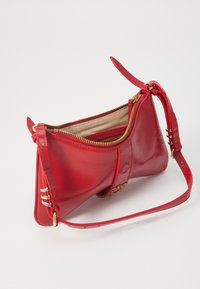 Red leather handbag with a unique triangular shape. Features a gold zipper and a detachable strap. Interior has a beige lining.