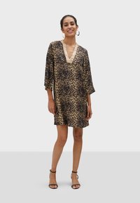 Haljina s leopard uzorkom, 3/4 zvonolikim rukavima, V-izrezom i teksturiranim zlatnim detaljima na izrezu. Lagani materijal, široka kroja. Crne sandale.