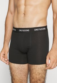 Schwarze Baumwoll-Boxershorts mit einem schwarzen Bund, der mit weißem "ONLY & SONS"-Text versehen ist. Der Stoff wirkt glatt und eng anliegend.