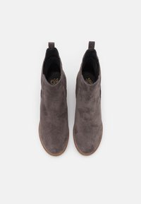 Bottines en suède gris avec panneaux latéraux élastiques, bout arrondi et texture douce. La semelle est marron clair avec des reflets de couture visibles.
