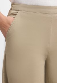 Beige broeken van gladde stof, met een zijzak, nette naden en een aansluitende taille, met een minimalistisch, hedendaags ontwerp.