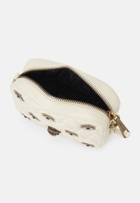 Borsa in pelle trapuntata bianca con cerniera aperta, decorata con motivi di occhi gioiello e un fermaglio a testa di serpente in bronzo.