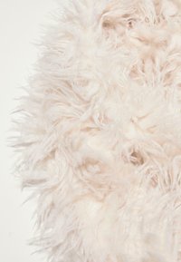 Tessuto soffice e leggero di colore crema, con lunghe fibre che creano un aspetto morbido e vellutato. Bordo arrotondato senza motivi o accenti visibili.