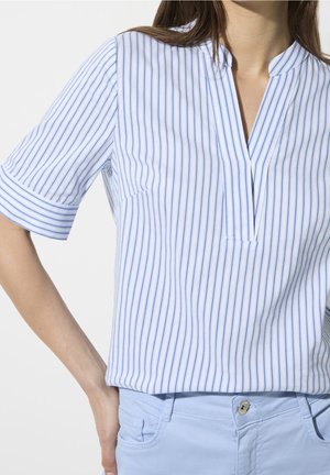 Camisa de manga corta con rayas azules y blancas, con cuello en v y puños remangados, hecha de una tela suave. Se lleva con pantalones azul claro.