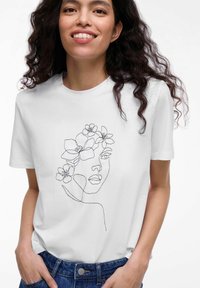 Witte katoenen T-shirt met een zwarte lijntekening van een vrouwenhoofd versierd met bloemen. Korte mouwen en een ronde hals.