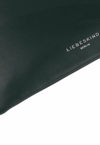 Ciemnozielony skórzany worek o gładkiej teksturze. Srebrne logo "LIEBESKIND BERLIN" nadrukowane na powierzchni. Minimalistyczny design, prostokątny kształt.
