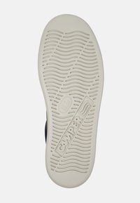 Sko sula i krämfärgat gummi med vågig slitbana. Har "Camper"-märke präglat på sidan, vilket visar märke och design.