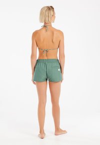 Zelené plavky s elastickým pásom a zadnou kapsou, skombinované s bikínami v štýle halter top s viazaním so vzorom.