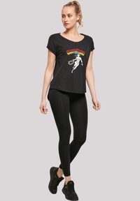 Sort T-skjorte med rund hals, prydet med et fargerikt "Wonder Woman"-grafikk. Kombinert med svarte tights og svarte treningssko.